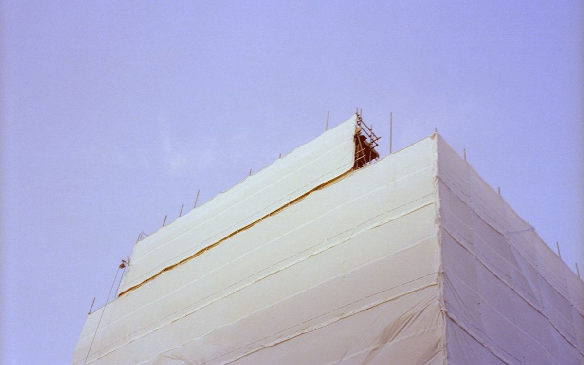 Building fully wrapped in white temporary roof sheeting